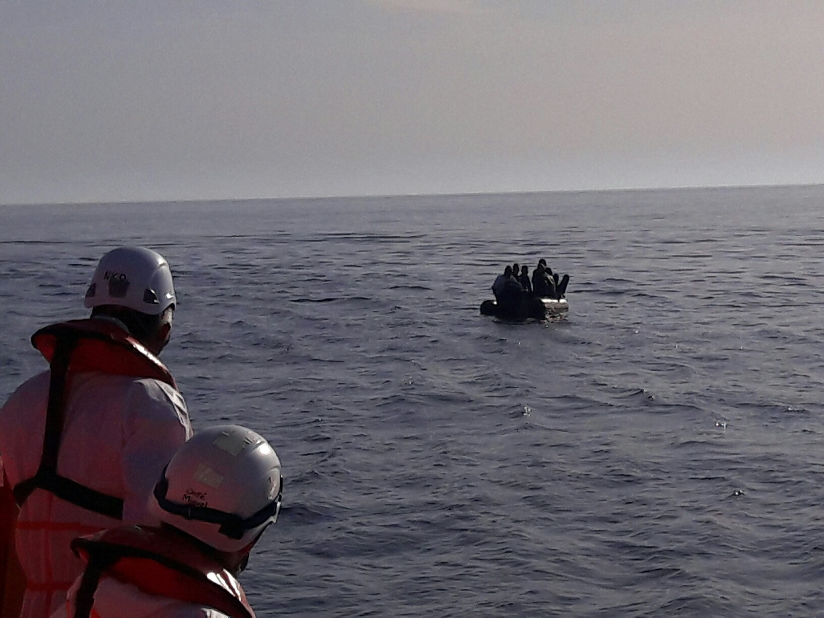 dos tripulantes de salvamento marítimo viendo una patera acercarse