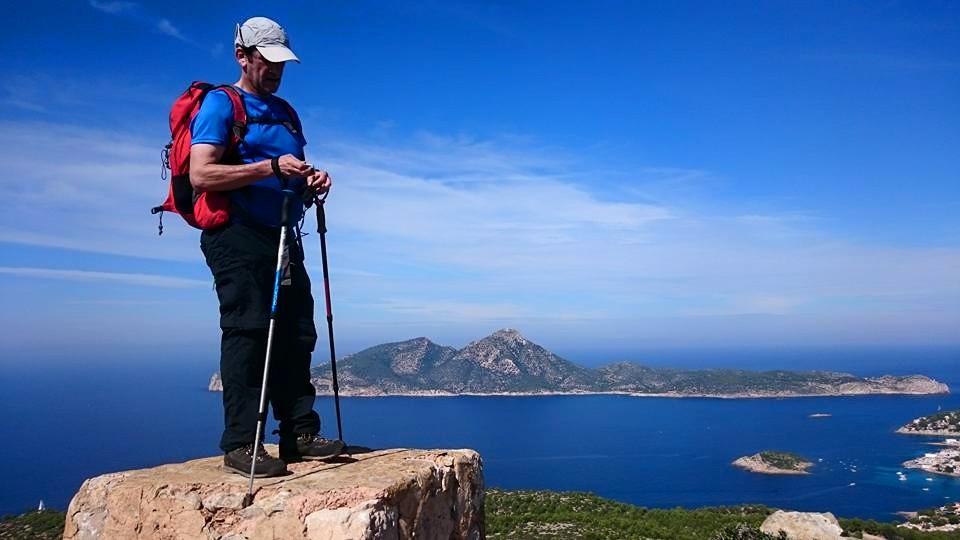 excursionista en la cima con fondo de cielo y mar azul