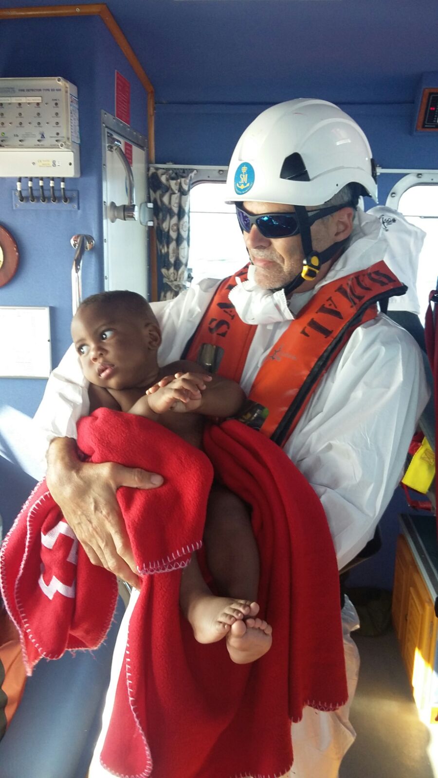 tripulante de salvamento marítimo con un bebé en brazos rescatado