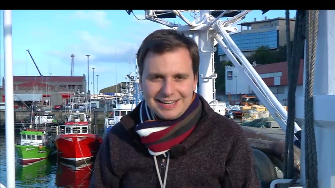 Hombre de mediana edad en un puerto con barcos de fondo