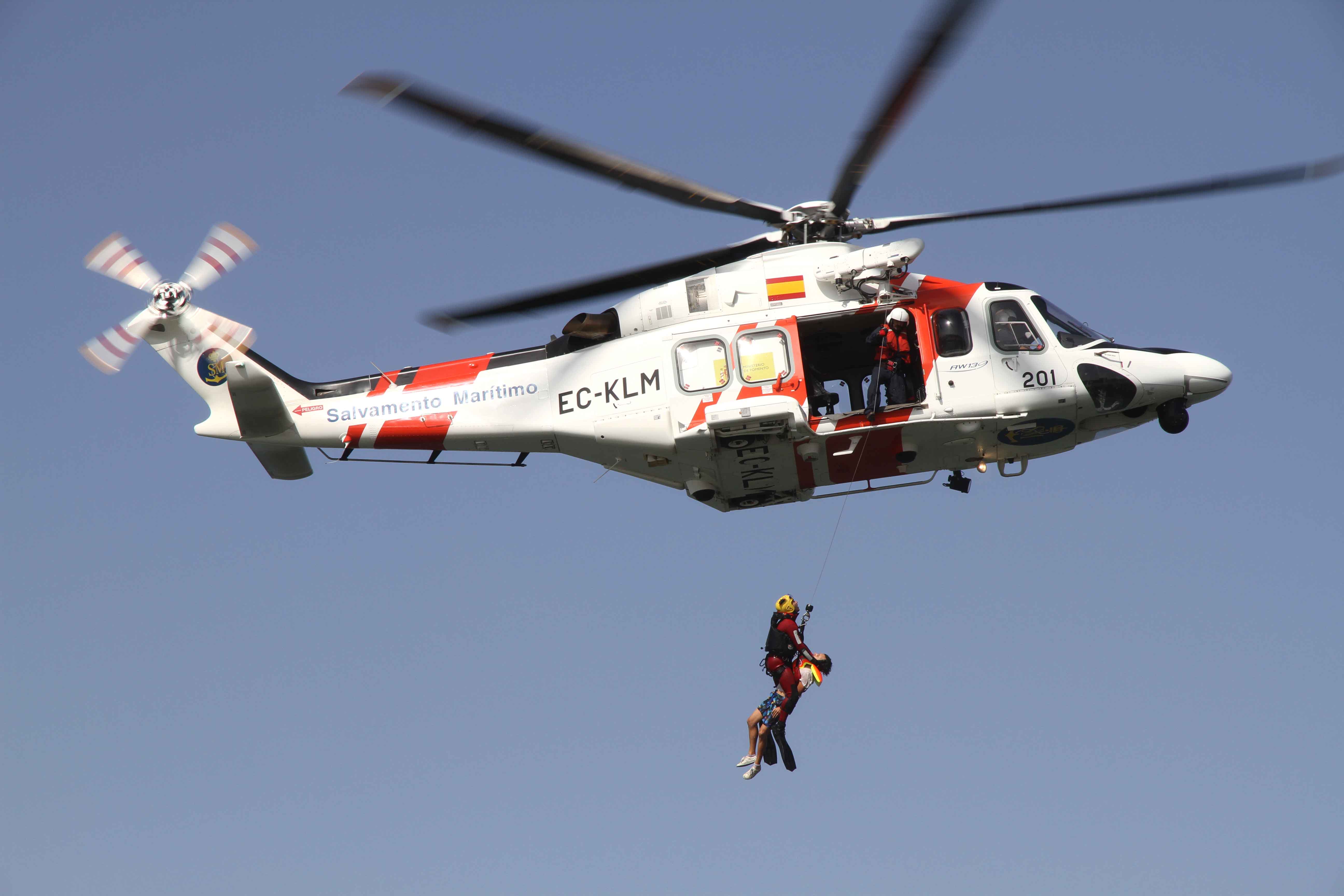 rescatador subiendo a auxiliado al helicóptero desde el mar