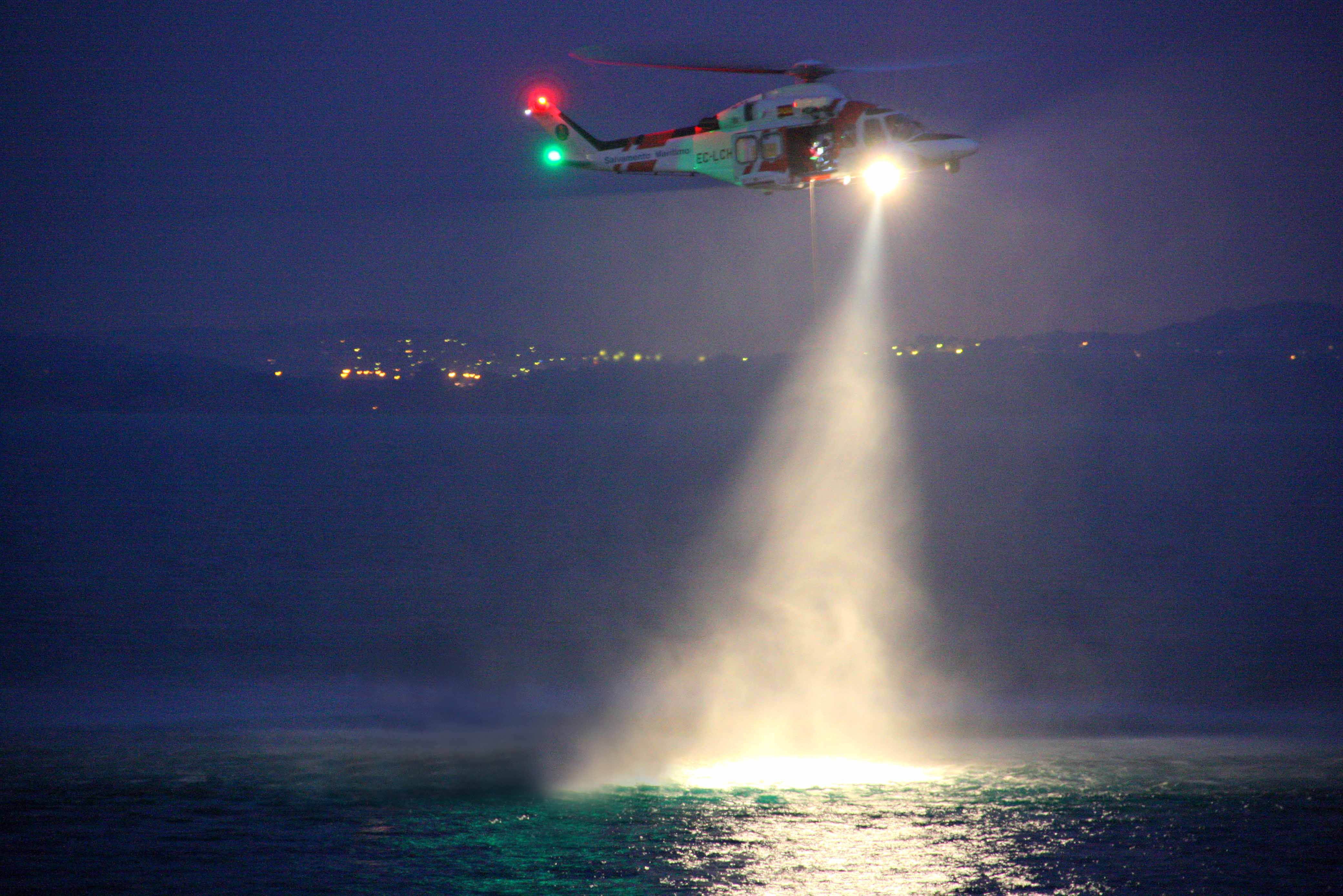 Helicóptero de noche iluminando mar