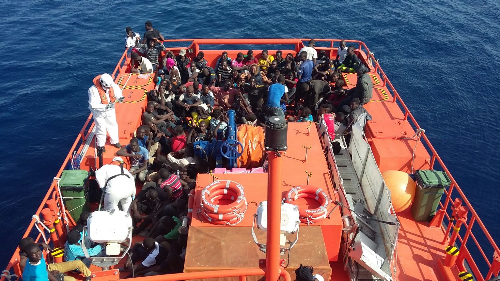 Grupo de personas subsaharianas en la cubierta de una Guardamar de Salvamento Marítimo, junto a tripulantes