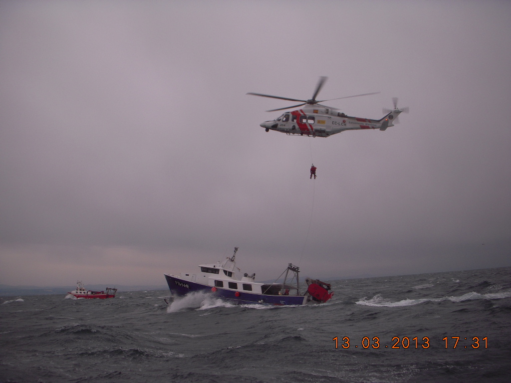 Rescatador bajando al pesquero desde helicóptero para una emergencia