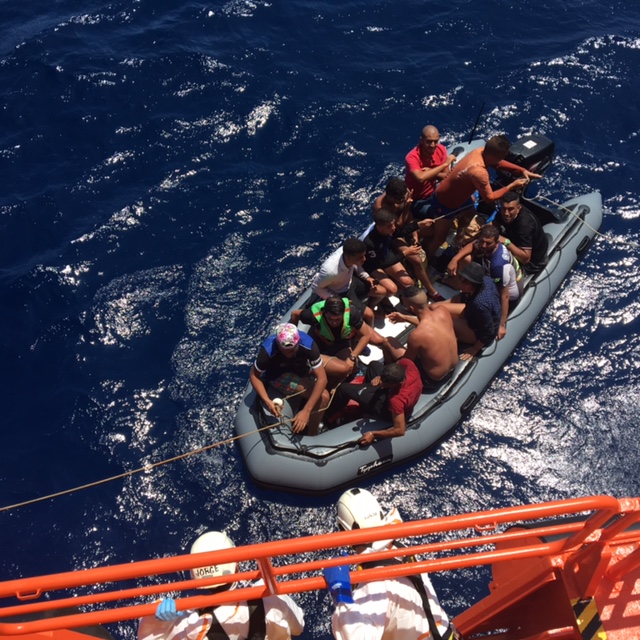 tripulación de sasemar acercando patera a su embarcación para su rescate