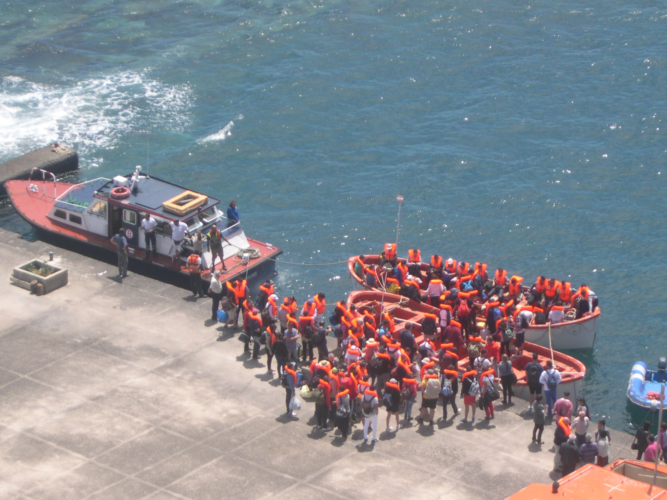 Tres embarcaciones en muelle con grupo de personas con chalecos salvavidas puestos