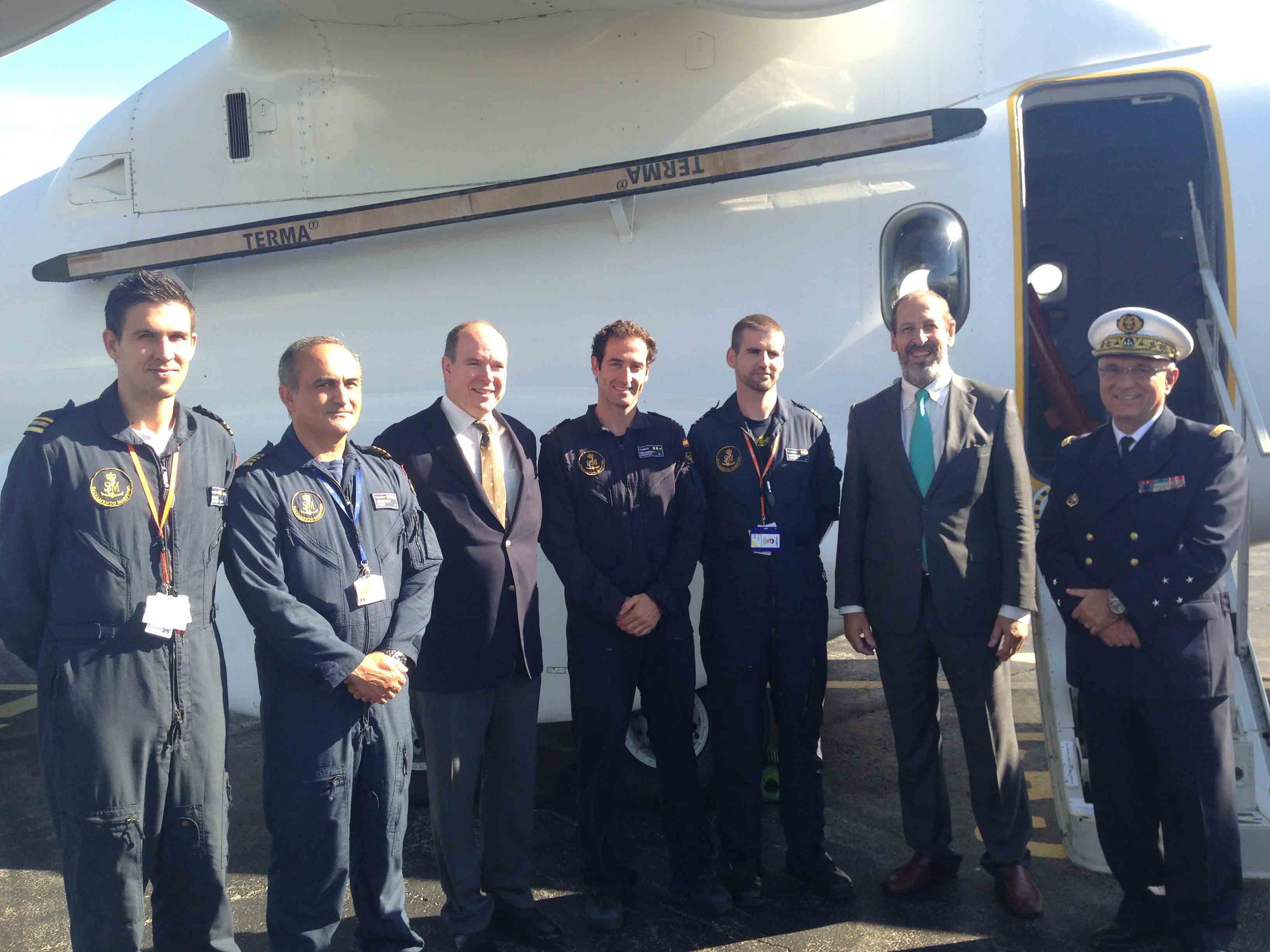 Grupo de hombres, entre ellos Alberto de Mónaco, en una pista delante de avión
